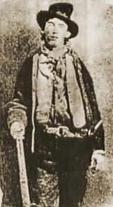William Bonney, also known as 'Billy the Kid' wearing hat and holding a stick