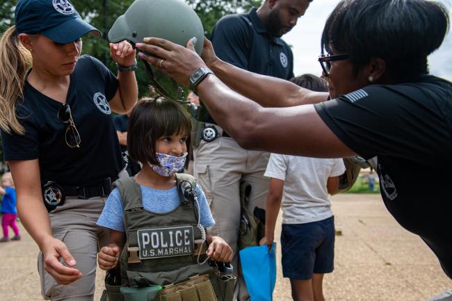 Deputy U.S. Marshals putting helmet on little girl during…