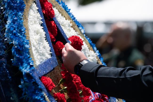 Man placing red carnation on wreath during the 2022 Peace…
