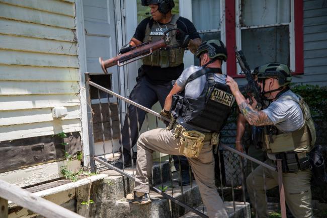Deputy U.S. Marshals using battering ram to gain entry to a…